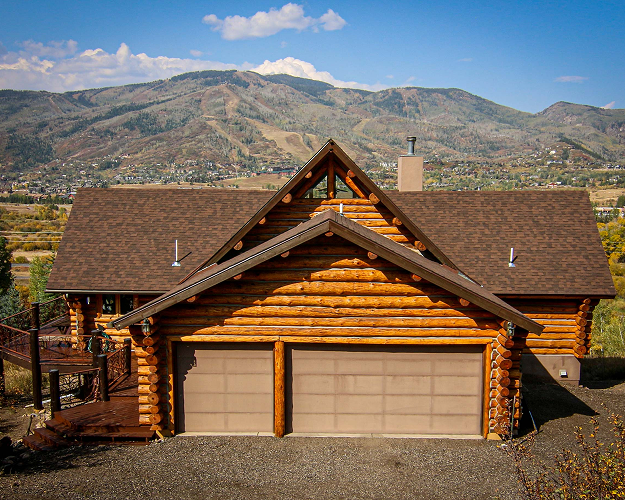 Premium residential roof replacement on a beautiful log home with a mountain backdrop