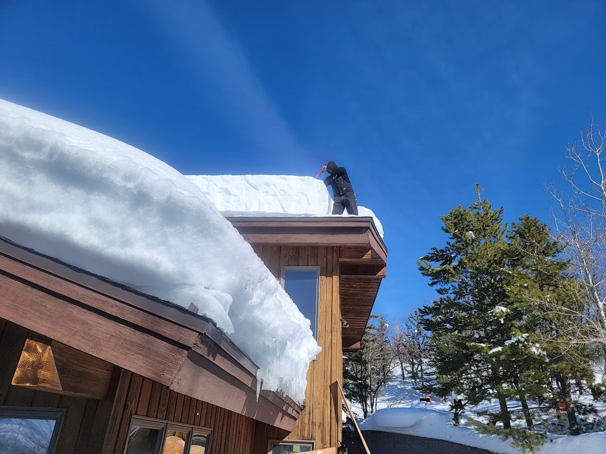 Worker removing heavy snow from a roof.