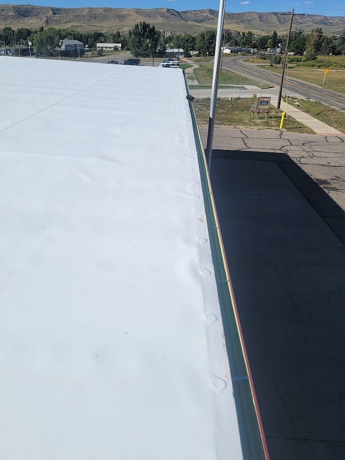 Commercial flat roofing system with a smooth white membrane installed on a commercial building in Steamboat Springs.