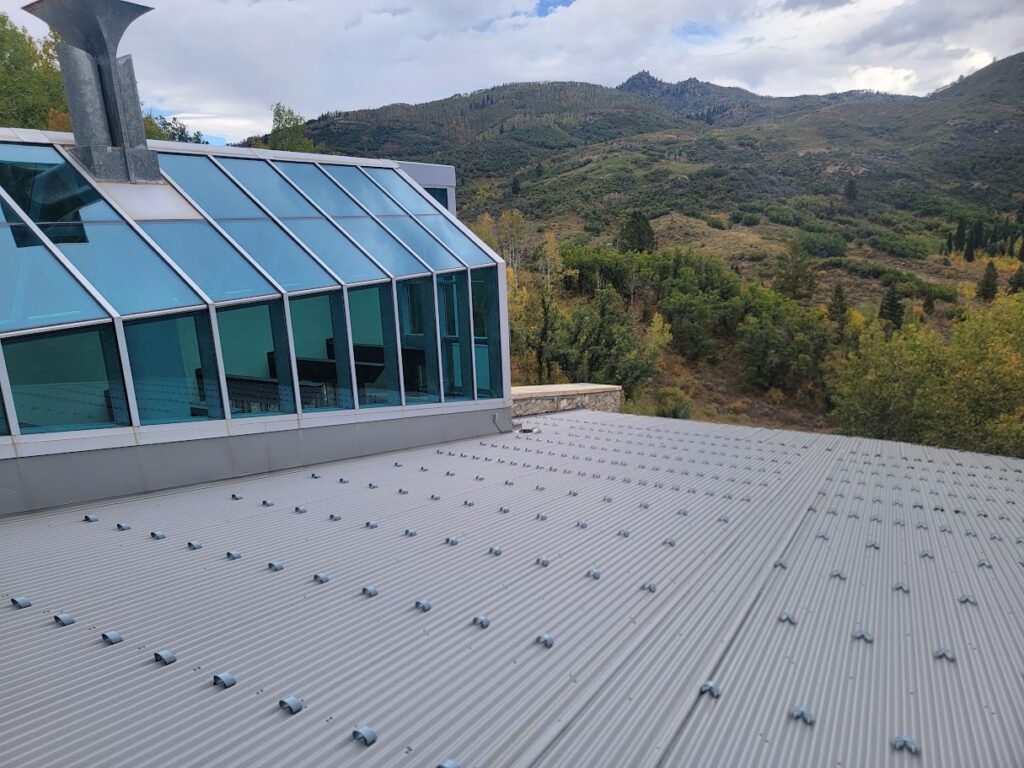 Commercial building with standing seam metal roofing and a glass atrium overlooking a high country mountain landscape in Colorado.